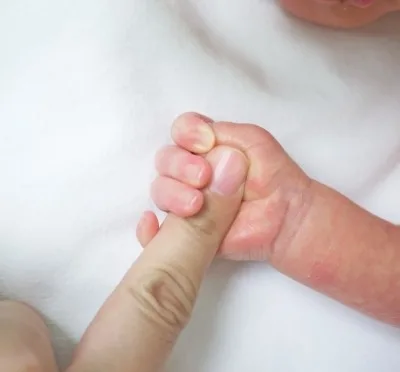 Ръчичка на бебе държи пръст на възрастен