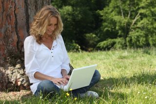 Жена, която пише на лаптоп сред природата